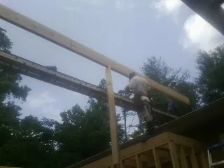 Carpenter setting a ridge beam over a new addition frame — Ice Dam Removal by Roofing Brothers in Stokes