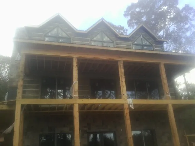 Dormers and porch framing on a large log home under construction — Roof Coating work by our crew in Stokes