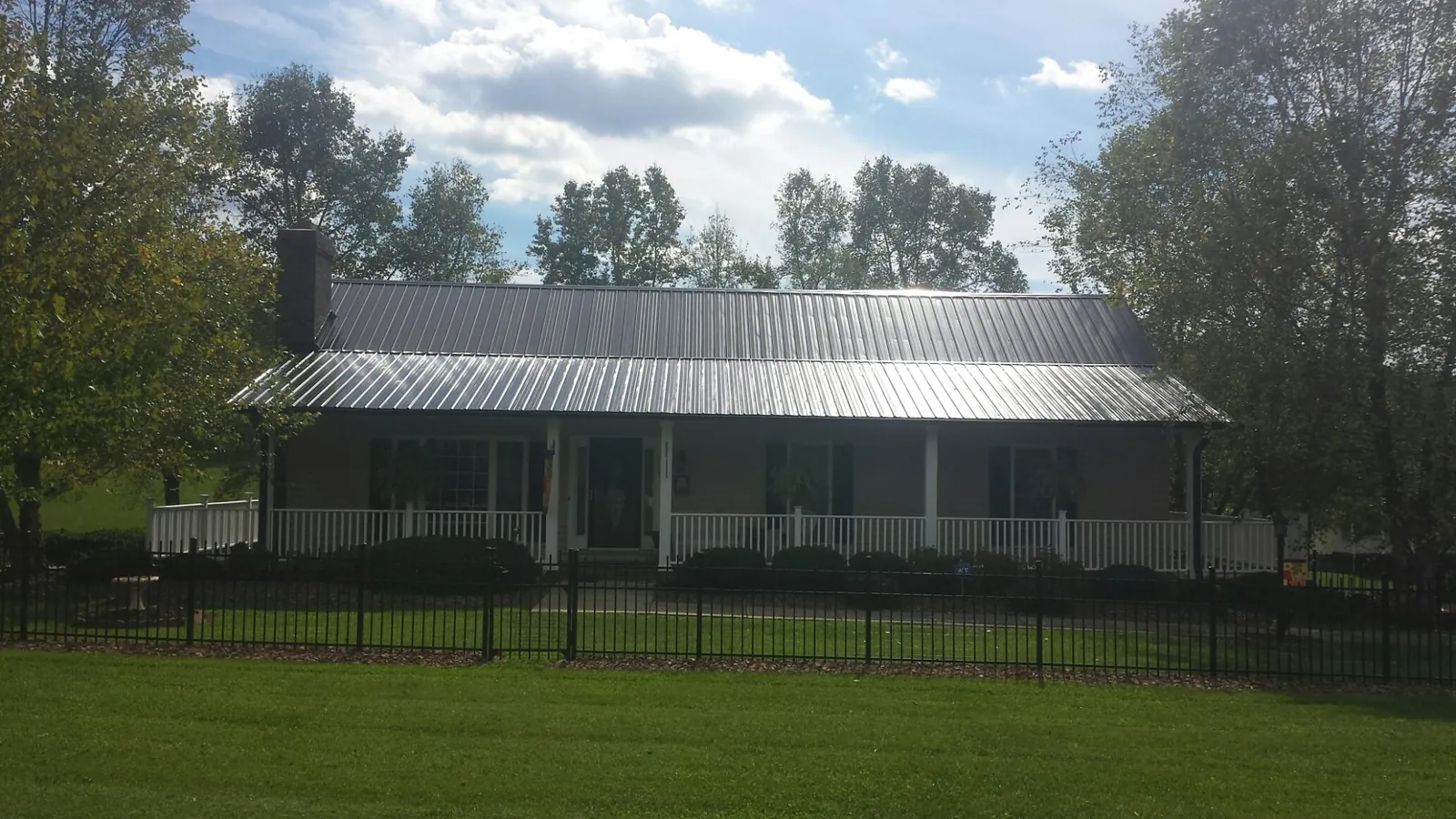 Gray metal roof on a brick ranch with a full width front porch — Gutter Guard Installation work by our crew in Stokes