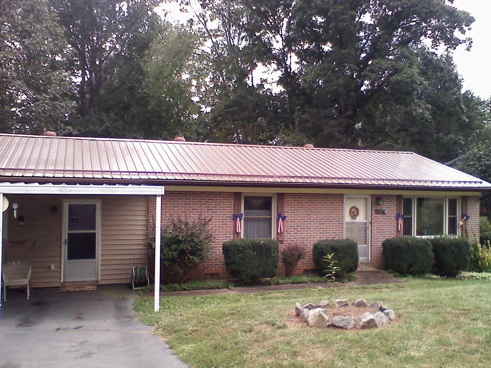 Bronze metal roof and carport on a brick ranch home — Roof Repair work by our crew in Stokes