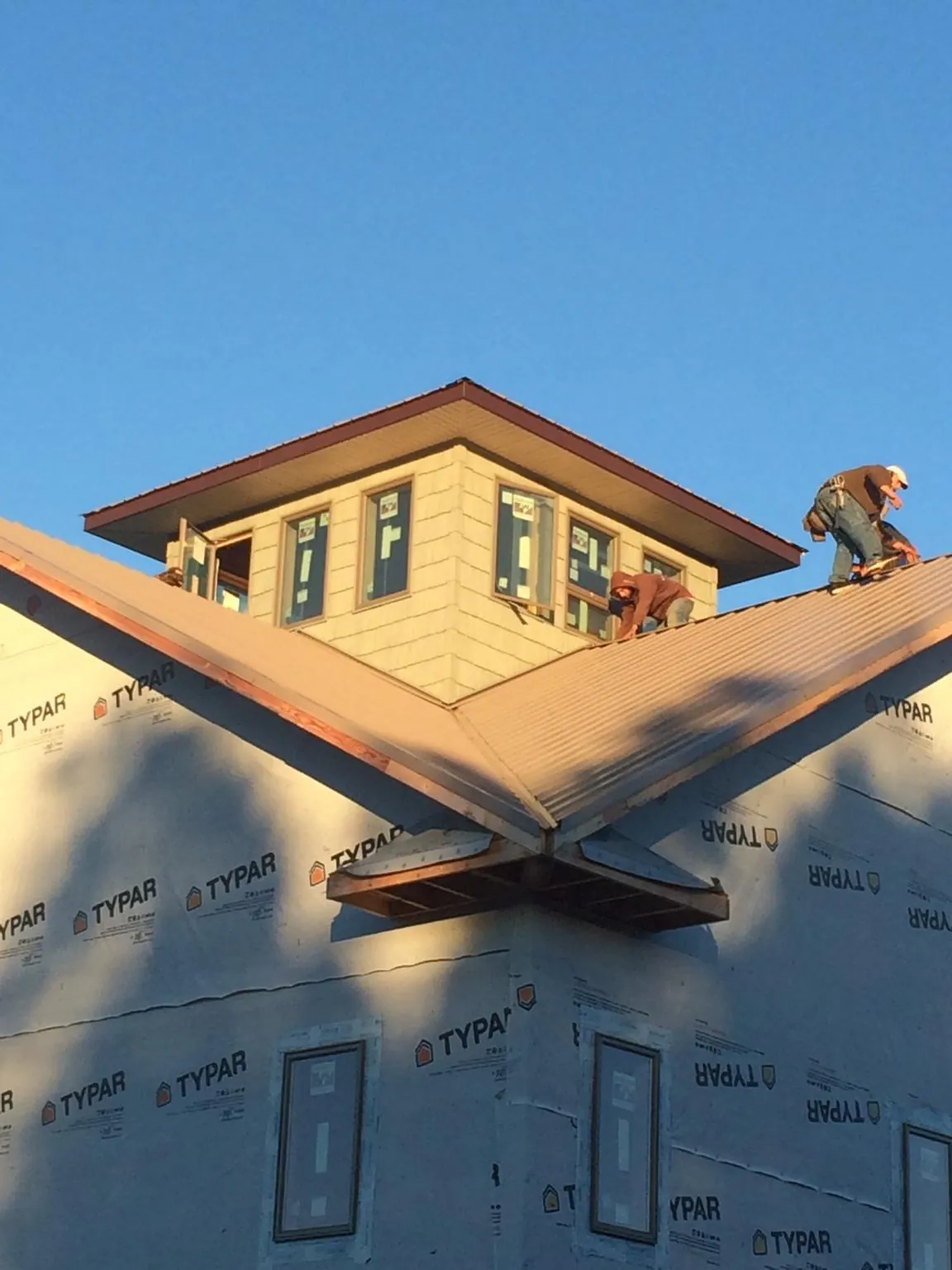 Roofers working around a rooftop cupola on a new metal roof at sunset — Roof Waterproofing in Stokes by Roofing Brothers